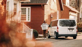 Woman handing off a basket for a laundry pickup service at her home in Bayville.