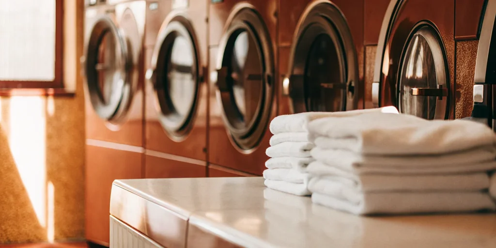 Best commercial laundry service in Manhasset featuring rows of washers and perfectly folded white towels.