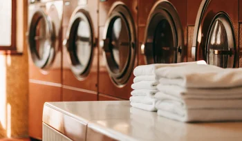 Best commercial laundry service in Manhasset featuring rows of washers and perfectly folded white towels.