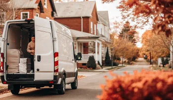 Laundry delivery service driver unloading bags from a van on a street in Upper Brookville.