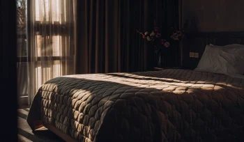 A professionally cleaned comforter on a cozy bed in a sunlit Carle Place bedroom.