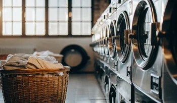 A basket of clean towels in front of machines at the best commercial laundry service in Wantagh.
