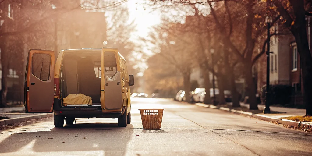 A laundry pickup service van collecting a basket of laundry in Upper Brookville.