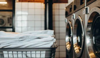 Basket of clean linens at a Carle Place medical laundry facility with industrial washers.