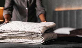 A professionally cleaned comforter being folded on a bed by a cleaning service expert in Hauppauge.