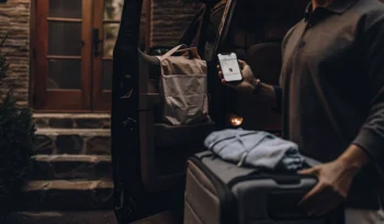 A laundry delivery service professional loads a laundry bag into a car in Cold Spring Hills.