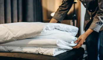Person folding a professionally cleaned white comforter in Herricks.