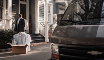 Laundry delivery service in Cove Neck delivering a box of fresh, folded clothes to a home.