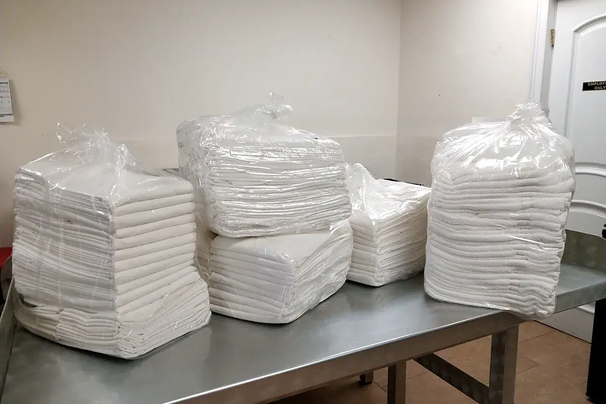 Bundled stacks of clean white commercial towels on the folding table in Glen Cove