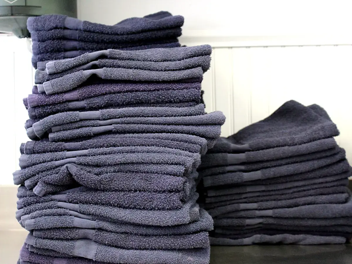 Stacks of folded gray gym towels ready for delivery at Long Island Laundry Company in Glen Cove